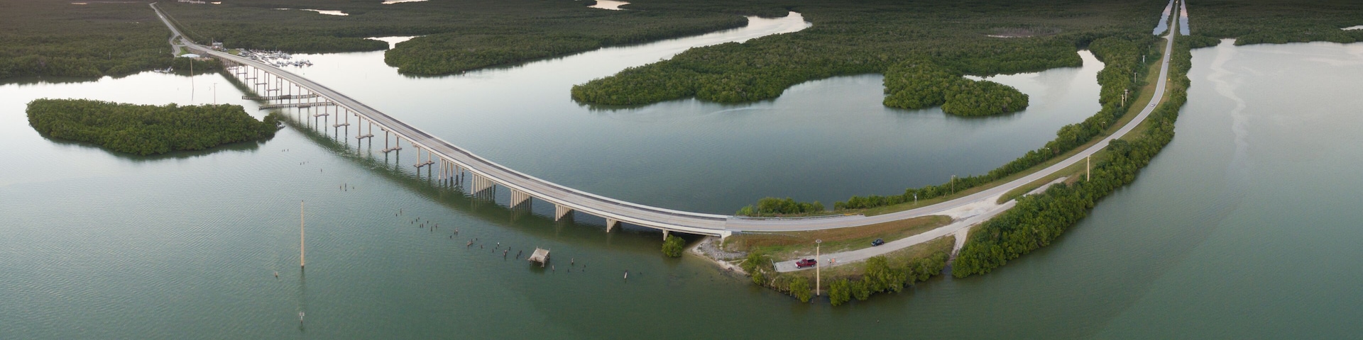 A long bridge curving through a mangrove-filled estuary.
