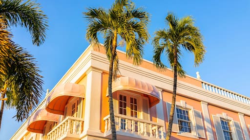 Old town Naples, Florida downtown on Third Street South shopping district with pink building architecture exterior at sunset with palm trees and baby blue sky