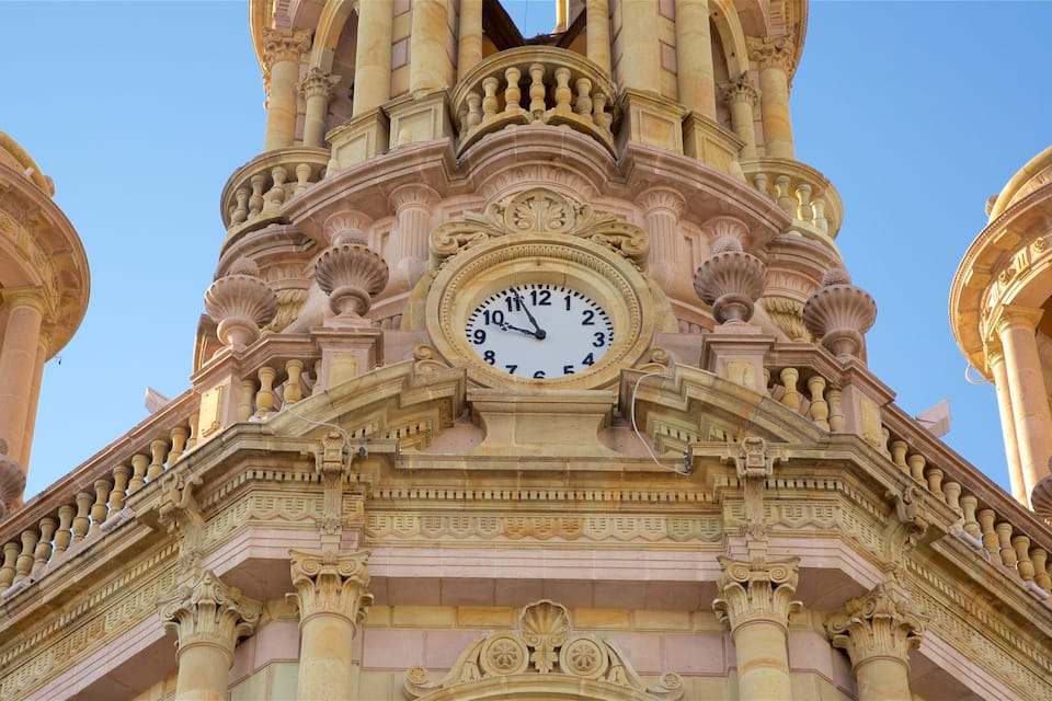 Una torre del reloj con detalles arquitectónicos ornamentales y dos torres más pequeñas a cada lado.