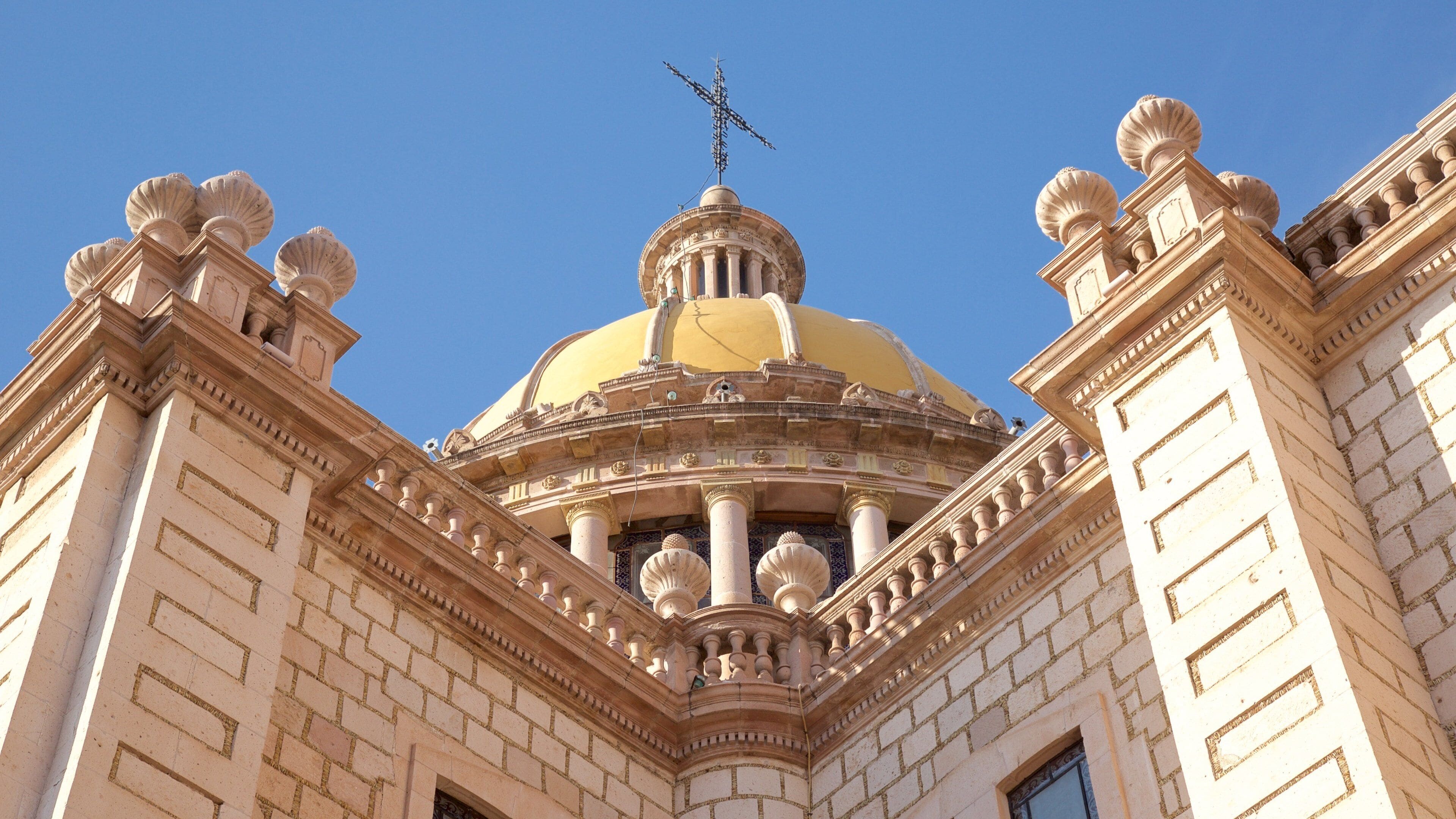 A grand building with a large yellow dome and ornate columns.
