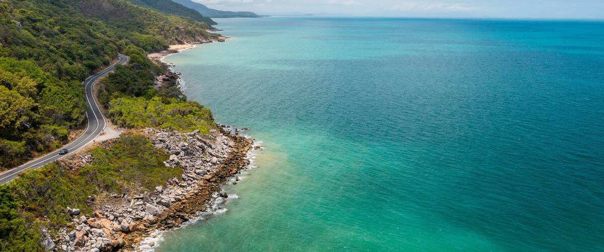 A coastal road winding through a mountainous landscape with turquoise waters.