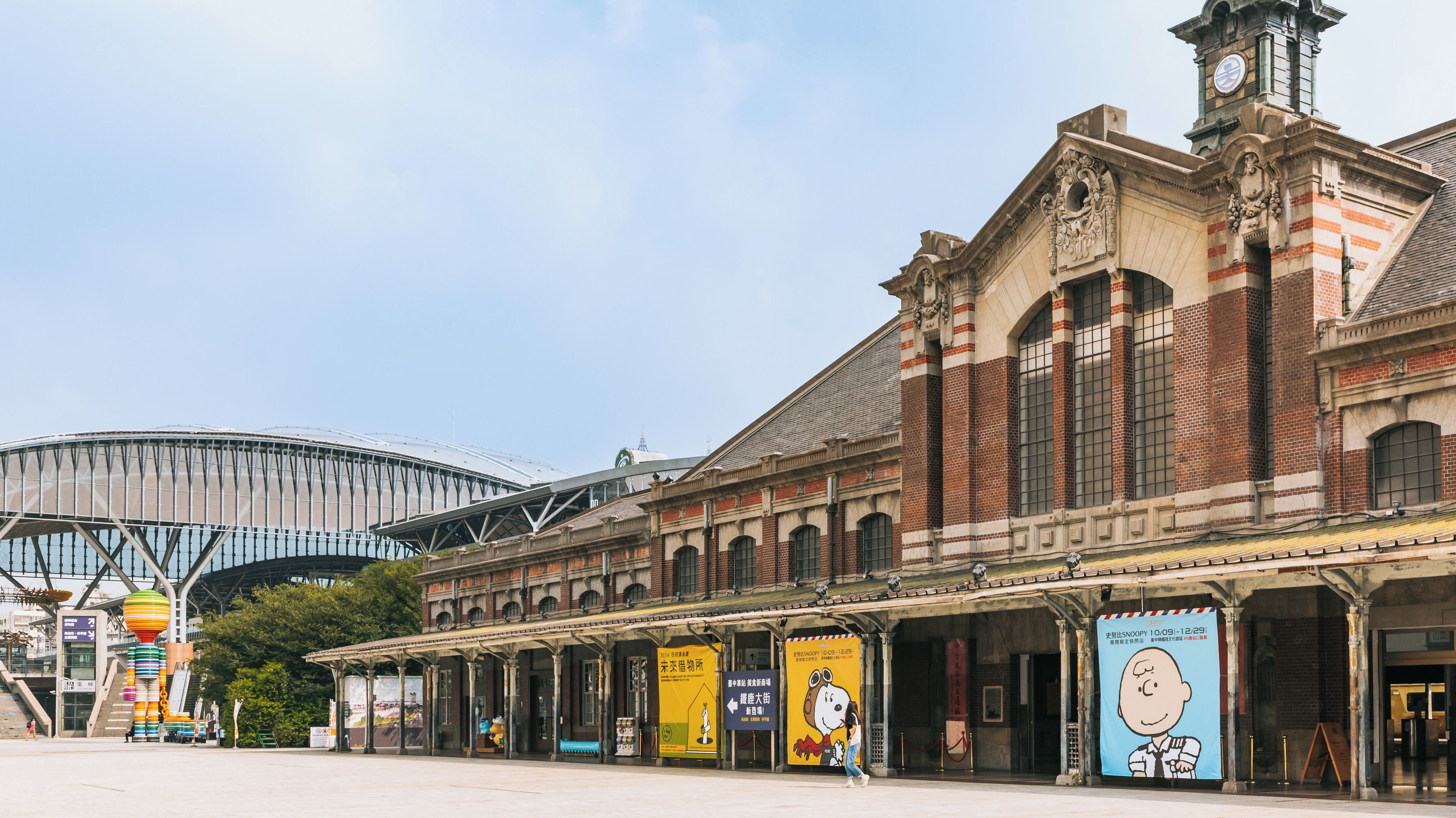 Un bâtiment historique doté d’une tour horloge, d’une galerie couverte et, au loin, d’un stade moderne.