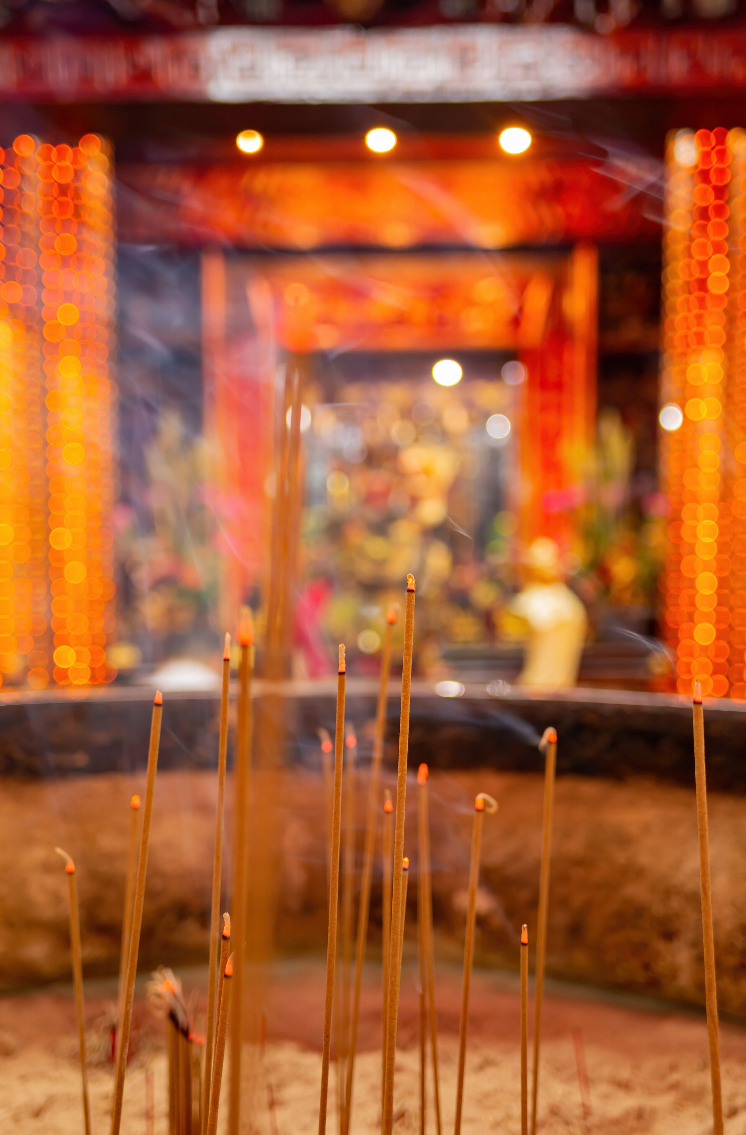 Incense sticks in a temple with blurred background decorations.