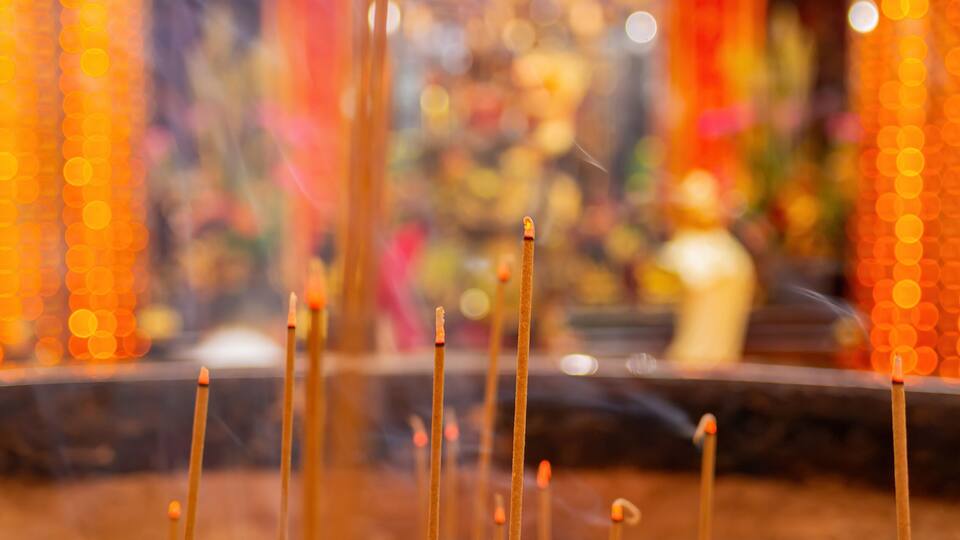 Incense sticks in a temple with blurred background decorations.