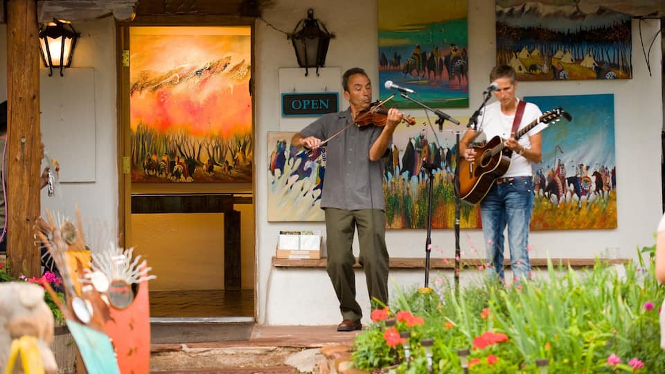 Twee muzikanten treden op op een veranda met levendige schilderijen en een bord waarop