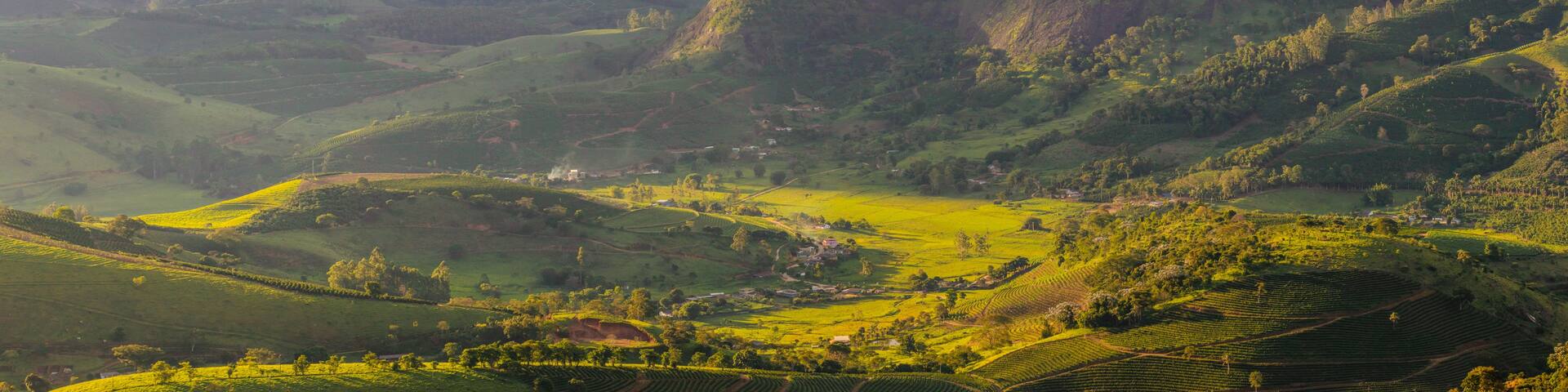 A mountainous landscape with terraced fields and a prominent rocky peak.