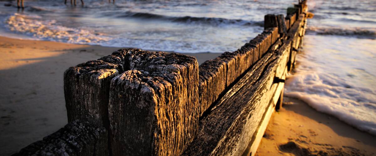 A wooden pier extending into the ocean with waves crashing against it.
