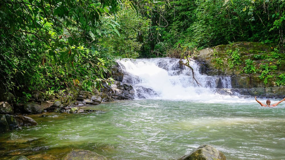 Woman bathing in a river by a waterfall. Costa Rica