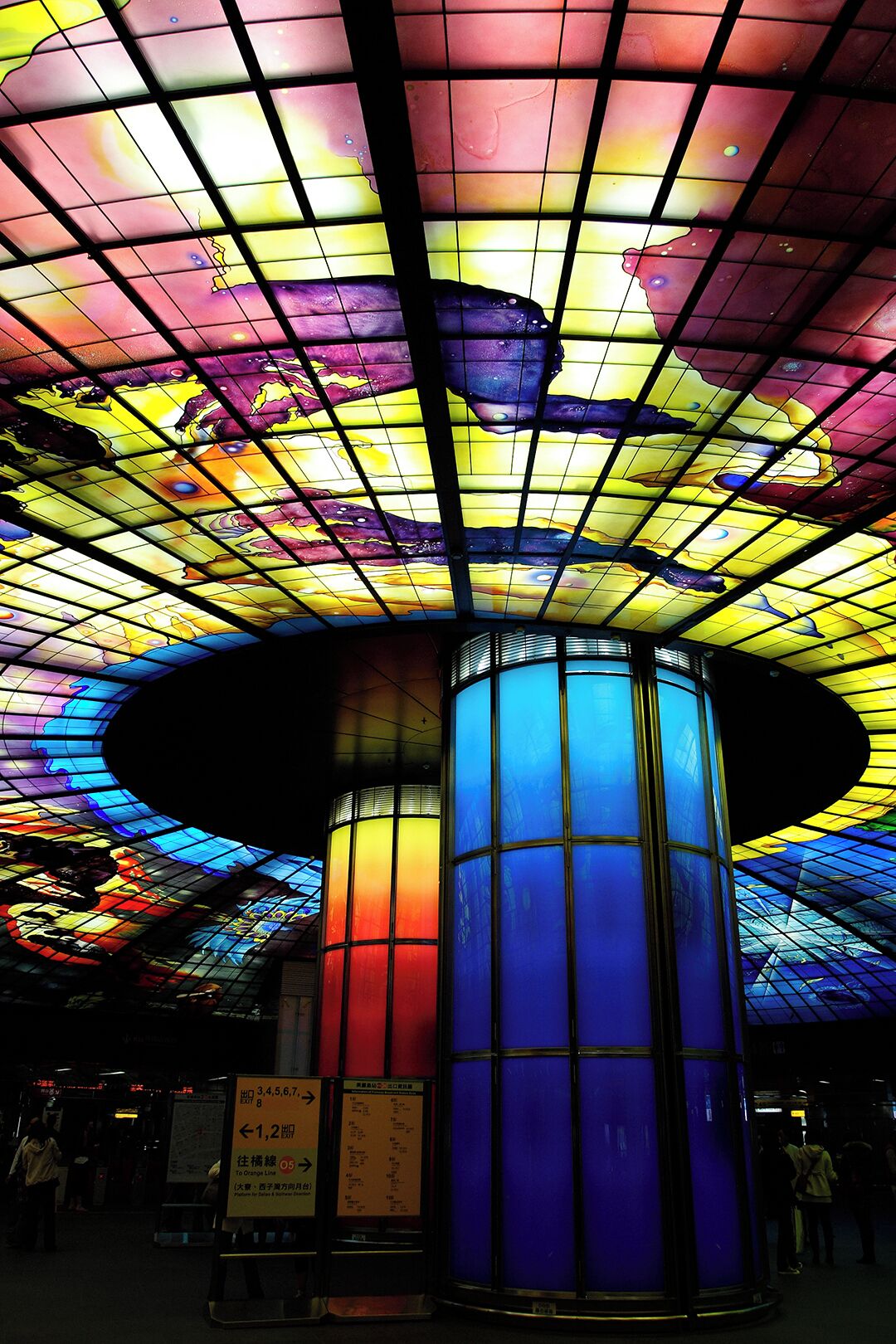 A colorful stained glass ceiling with a central cylindrical column.