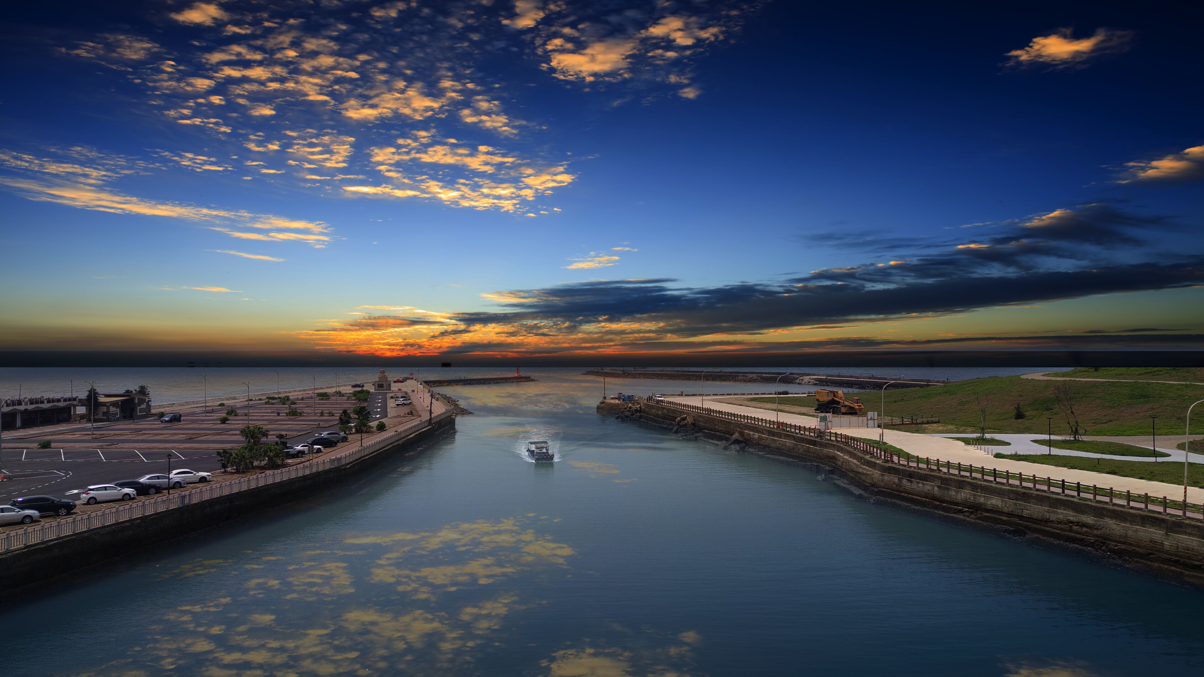 Un atardecer sobre un cuerpo de agua tranquilo con una carretera y un puente.