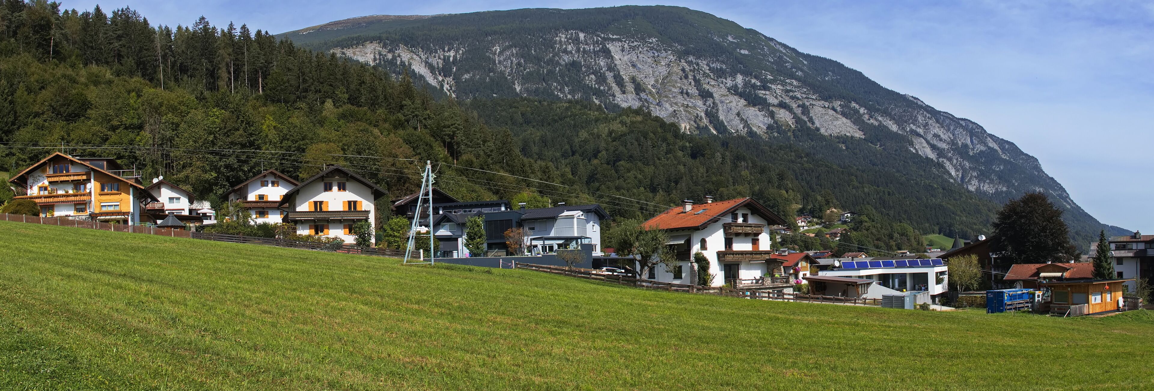 A hillside village with houses, a mountain, and a forest.