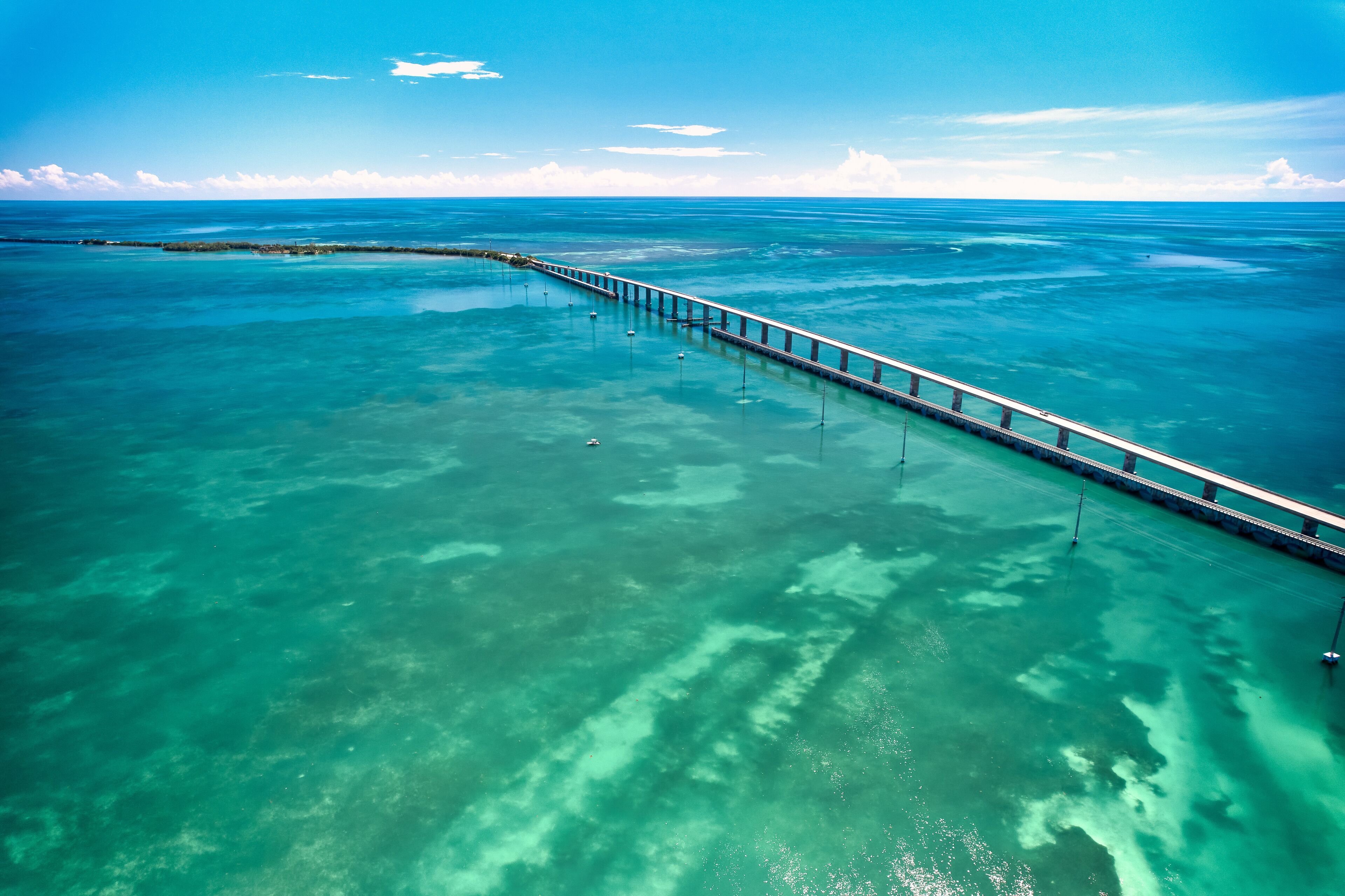 A long pier extending into turquoise waters with clear skies.