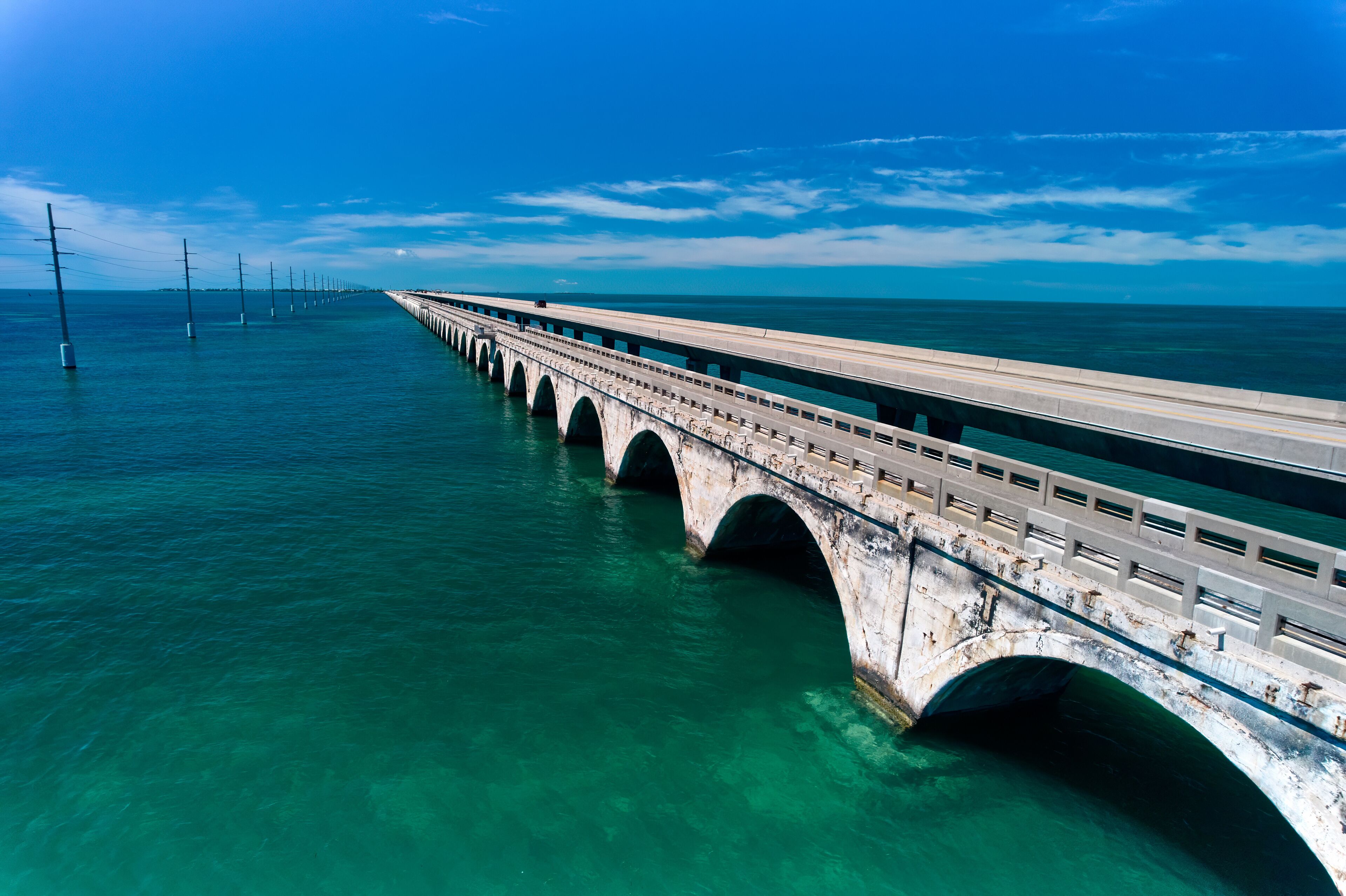 A long bridge over turquoise water with a clear sky.