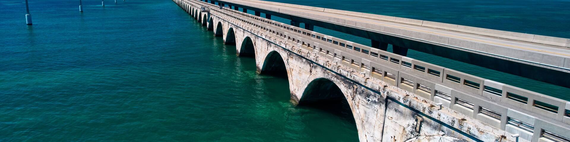 A long bridge over turquoise water with a clear sky.
