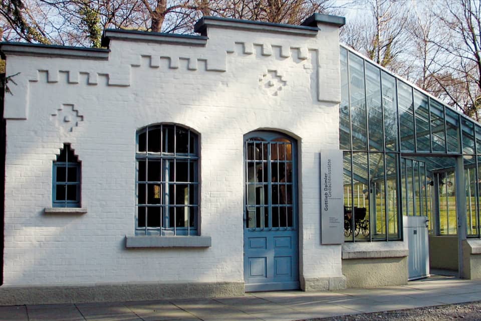 A white building with blue windows and a glass greenhouse structure.