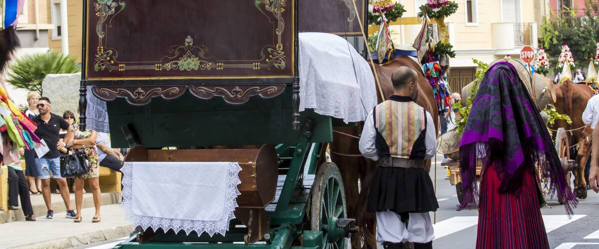 A traditional horse-drawn carriage with ornate decorations, a green frame, and a white cloth covering the seat.