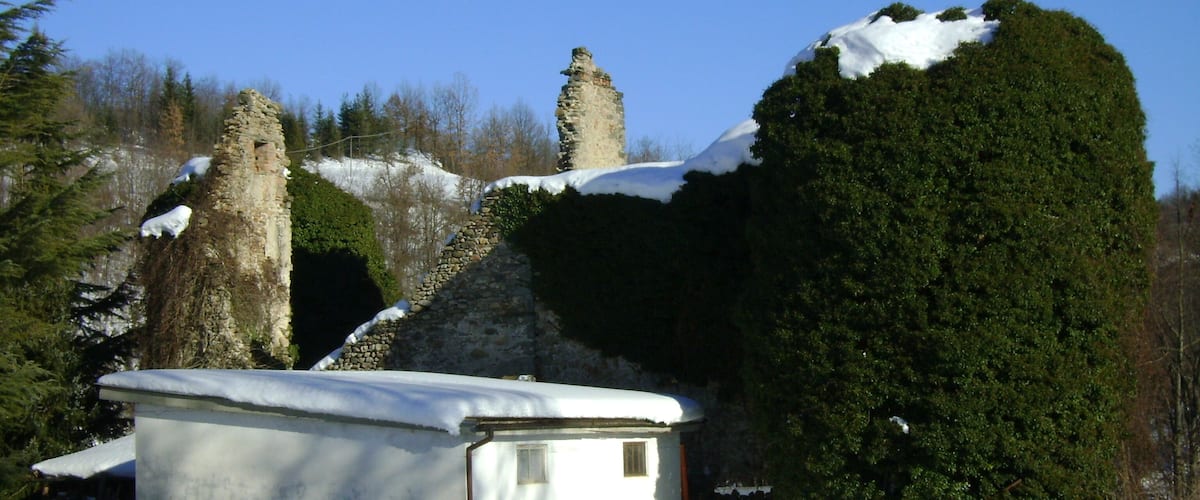 A snow-covered landscape with a stone ruin and a small white building.