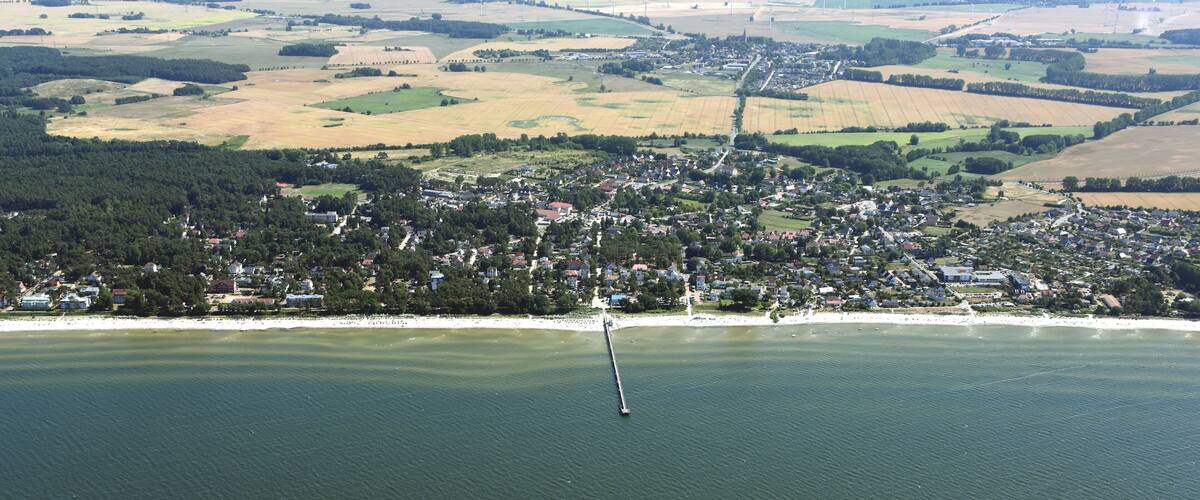 An aerial view of a coastal town with a lighthouse, surrounded by fields and a body of water.
