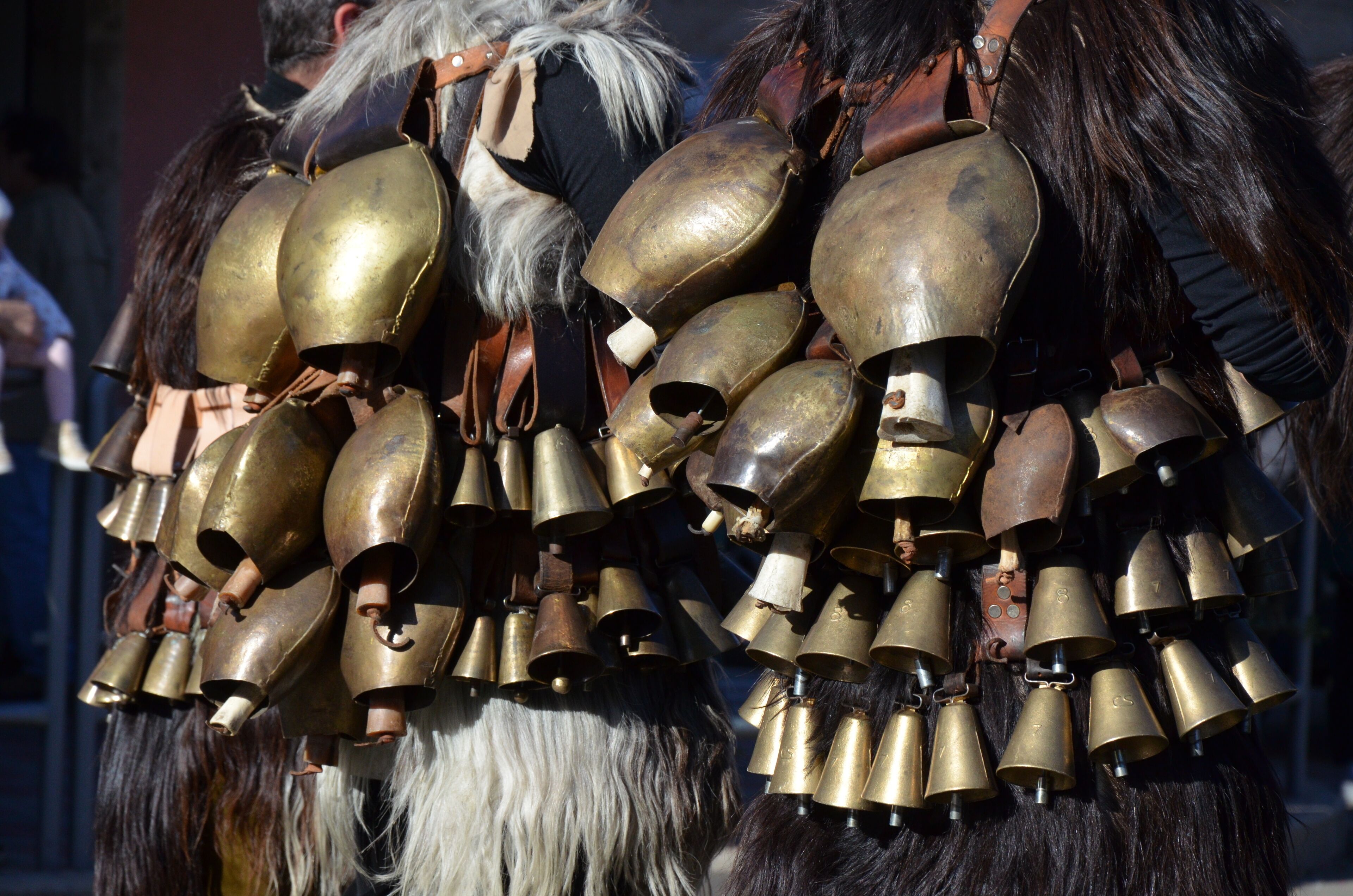 A person wearing a large number of brass bells attached to their costume.