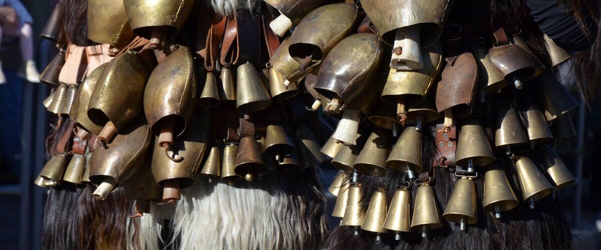 A person wearing a large number of brass bells attached to their costume.