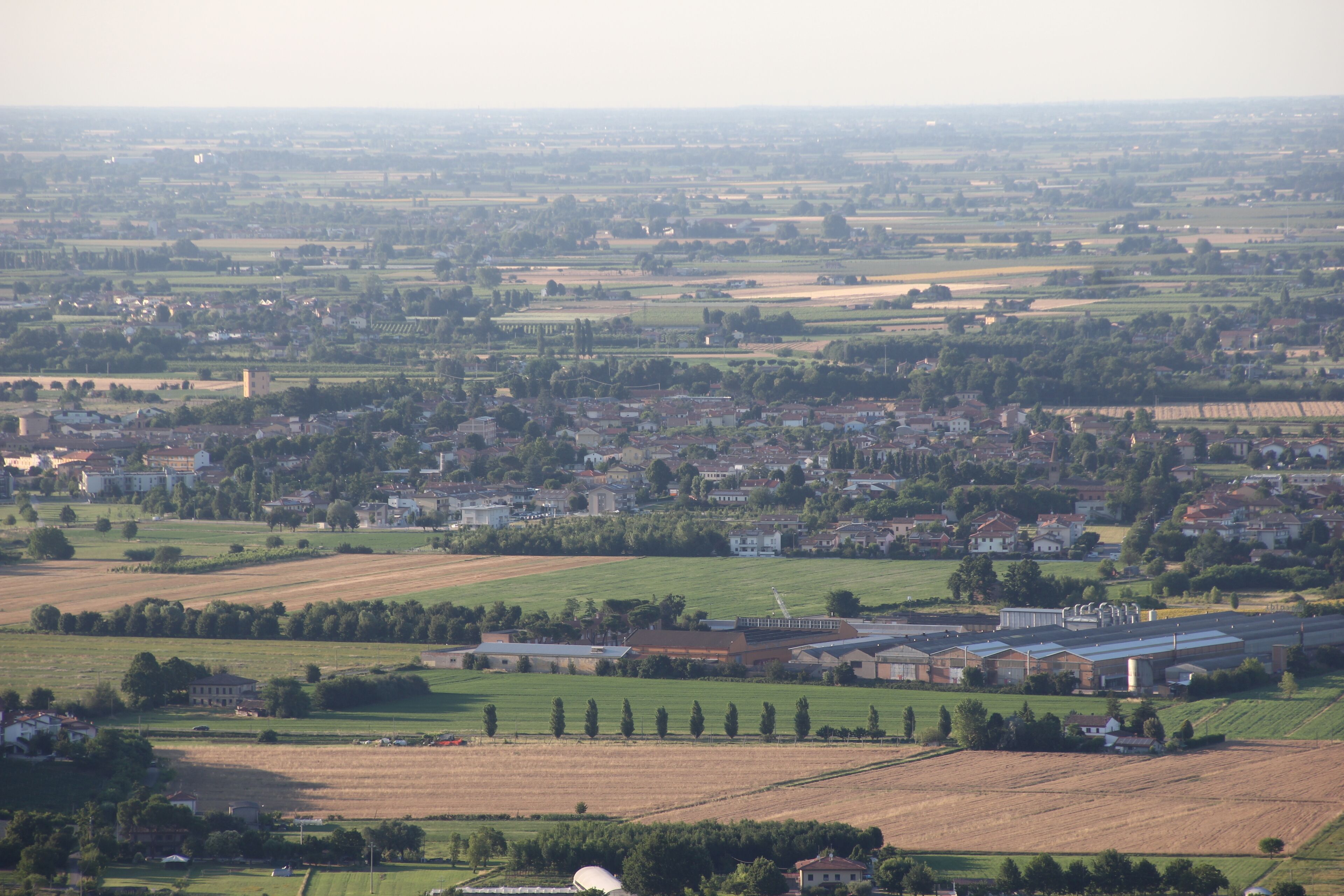 A rural landscape with fields, a small town, and a large industrial building.