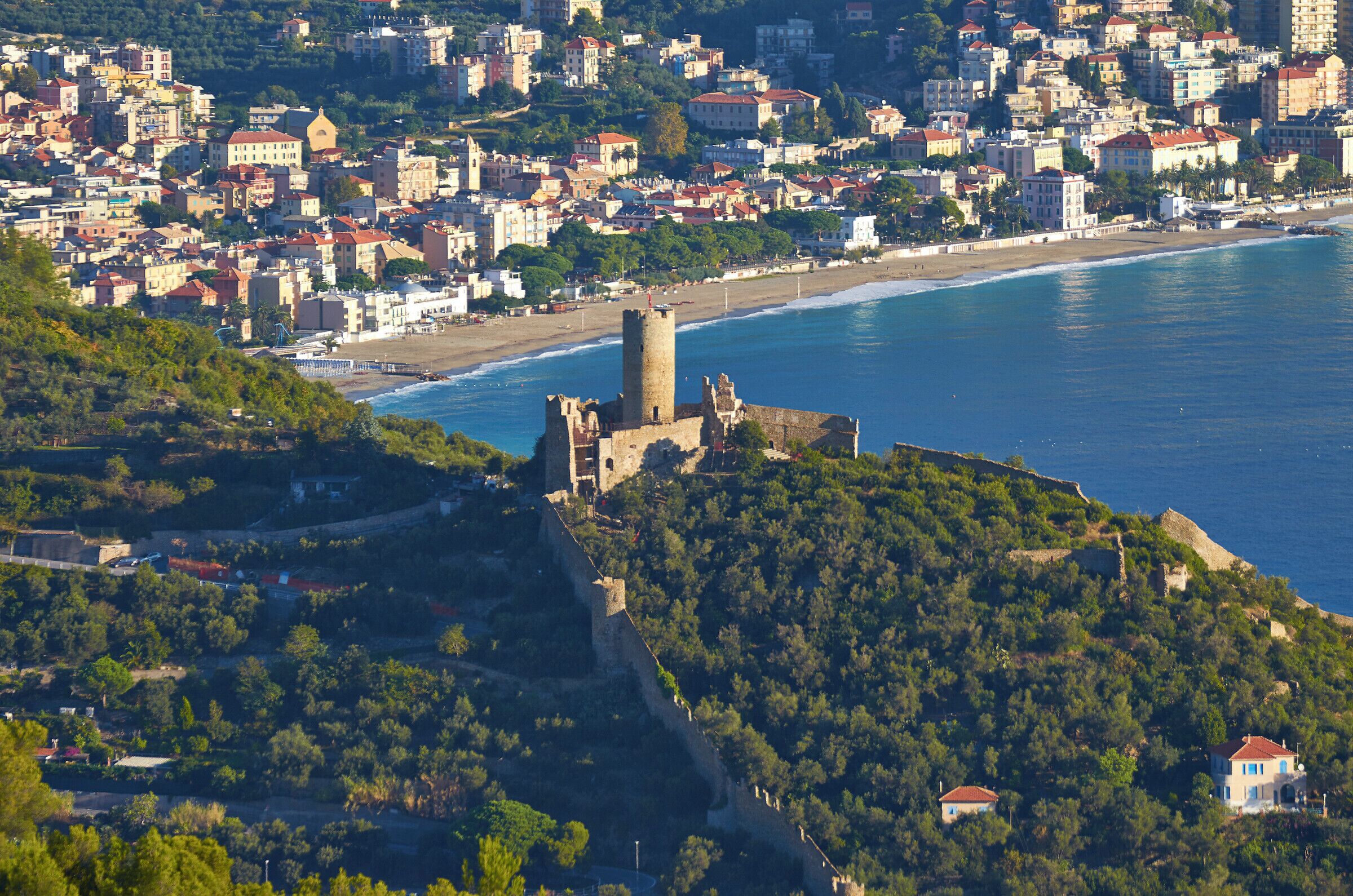 A coastal city with a historic castle on a hill overlooking the beach.