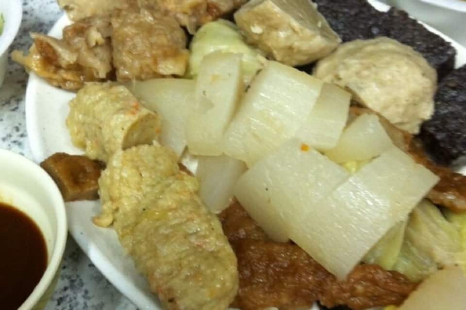 A plate with various food items including tofu, vegetables, and meat, accompanied by small bowls of sauces.