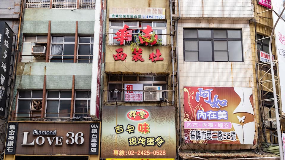 A row of commercial buildings with various signs and advertisements.