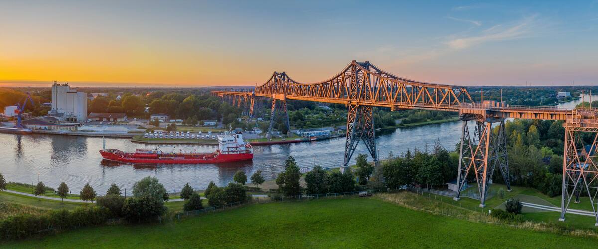 Un río con un puente grande y un barco rojo.