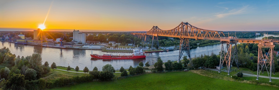 Ein Fluss mit einer großen Brücke und einem roten Schiff.