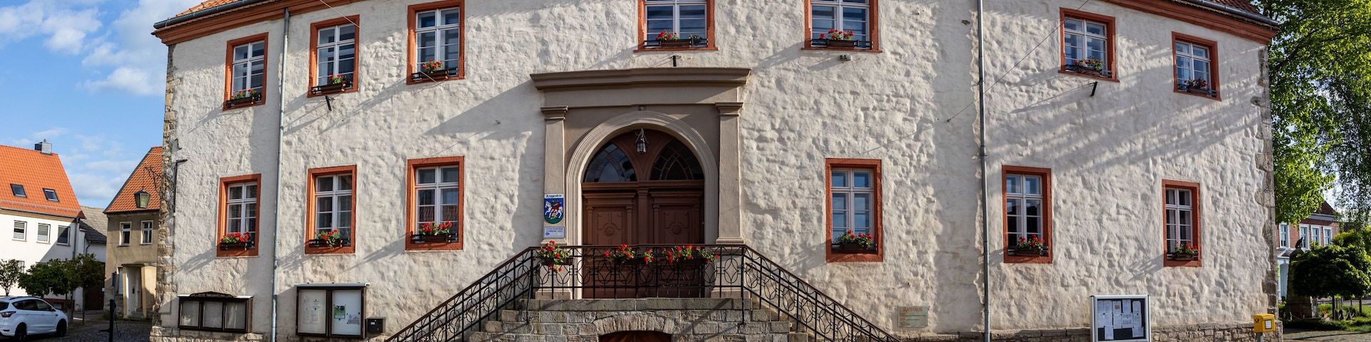 A historic building with a red-tiled roof, white stucco walls, and a central arched entrance.