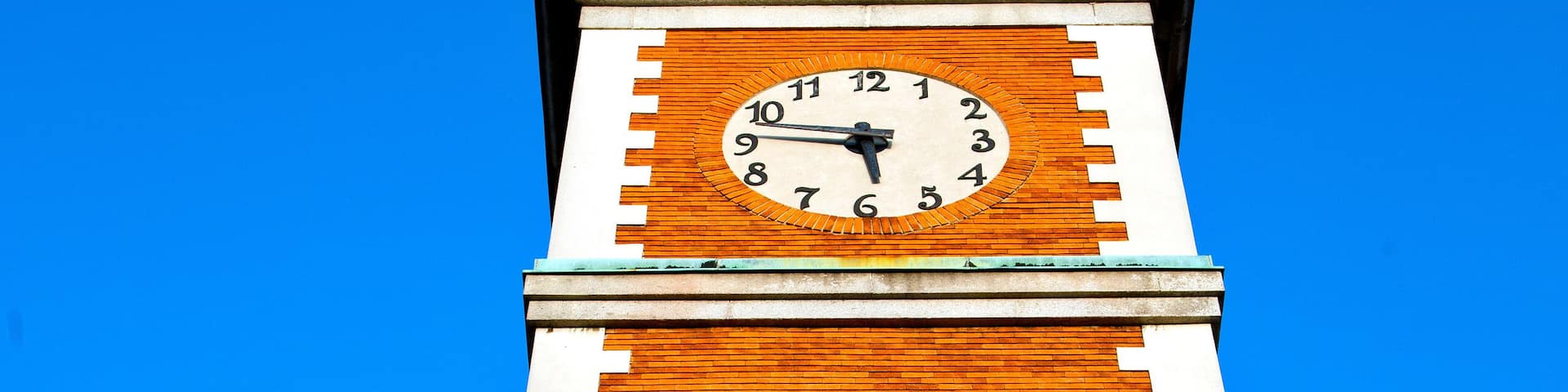 A tall brick tower with a clock and arched windows.
