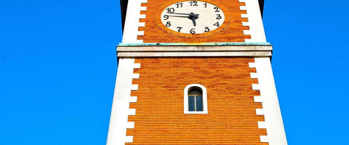 A tall brick tower with a clock and arched windows.