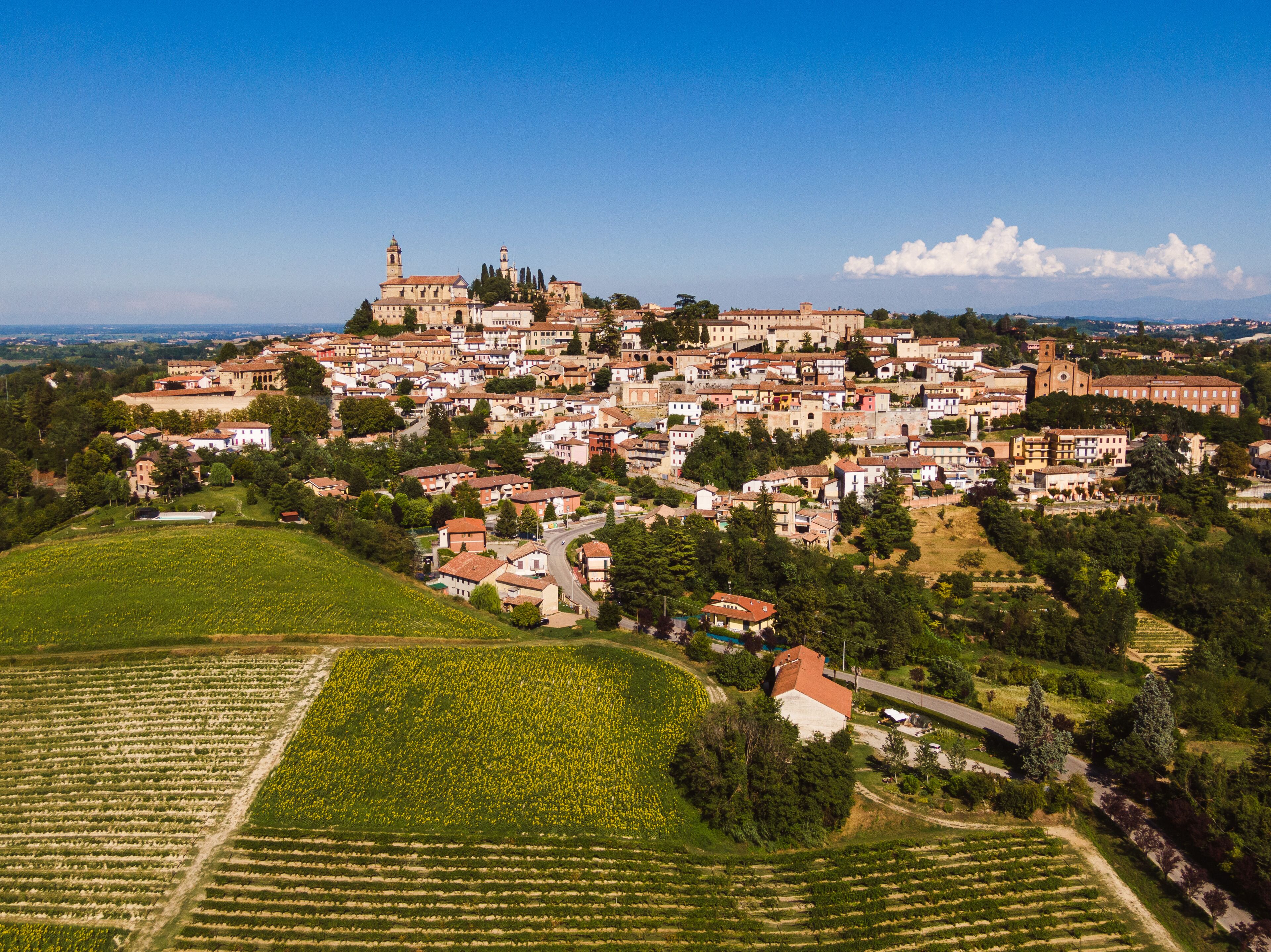 A town with a prominent church on a hill, surrounded by residential buildings and agricultural fields.