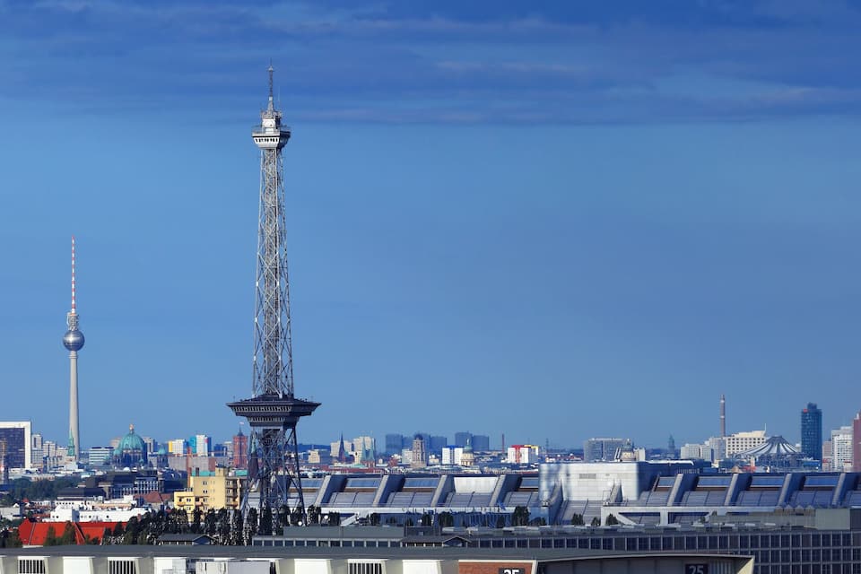 Un horizonte urbano con una torre destacada, edificios modernos y un estadio.
