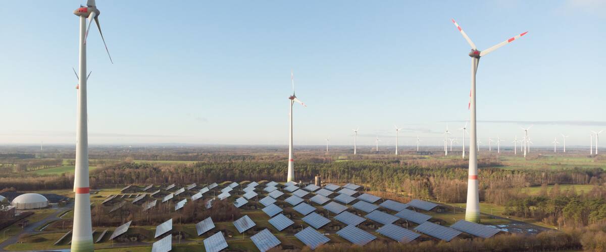 A wind farm with multiple wind turbines and solar panels.