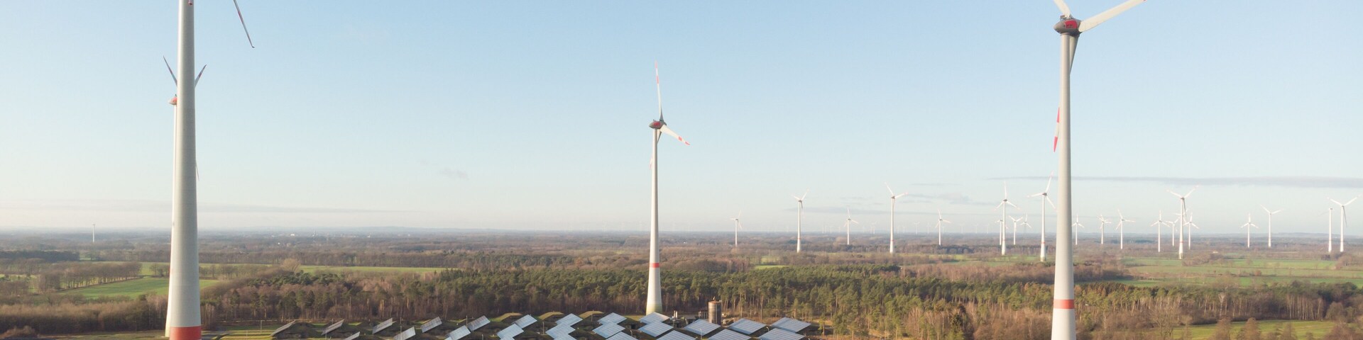 A wind farm with multiple wind turbines and solar panels.