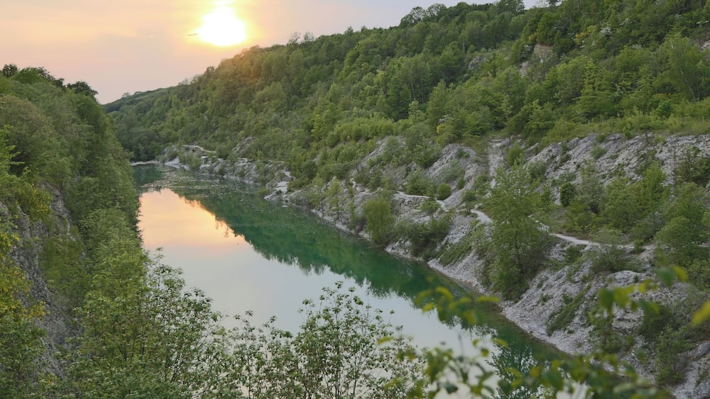 A river winding through a forested valley with a sunlit sky.