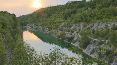 A river winding through a forested valley with a sunlit sky.