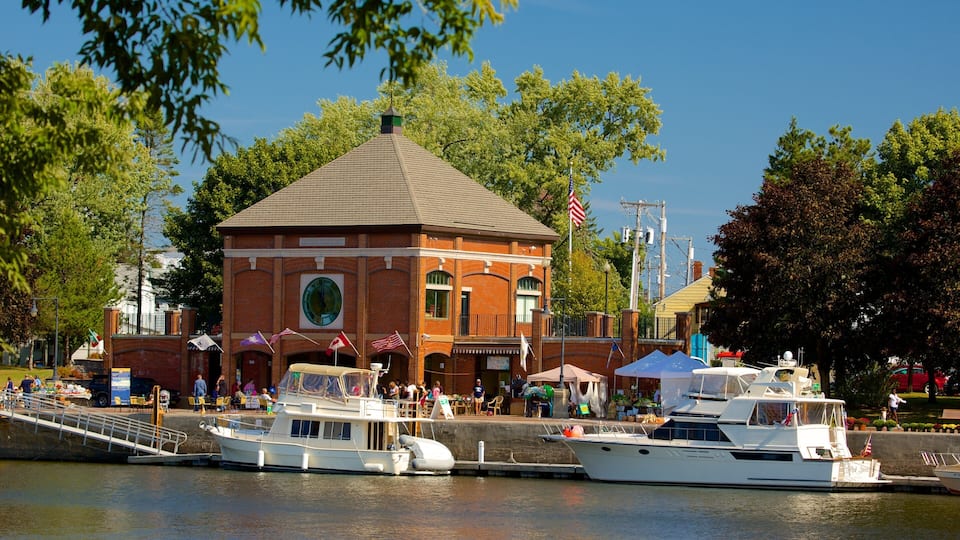 A brick building with a clock tower, a dock with boats, and a flag.