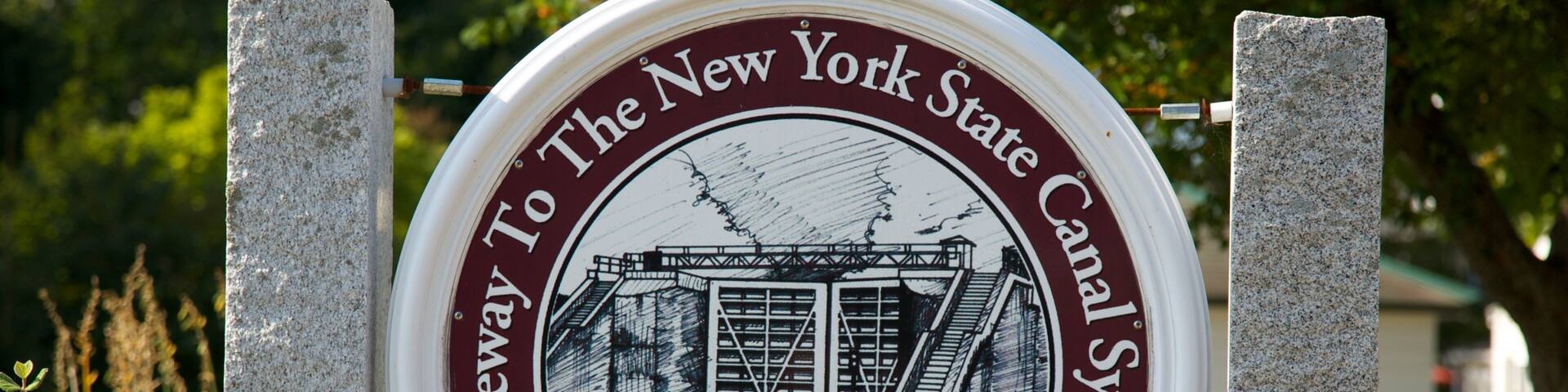 A circular sign with a historical illustration and the text "Gateway to the New York State Canal System" and "Waterford".