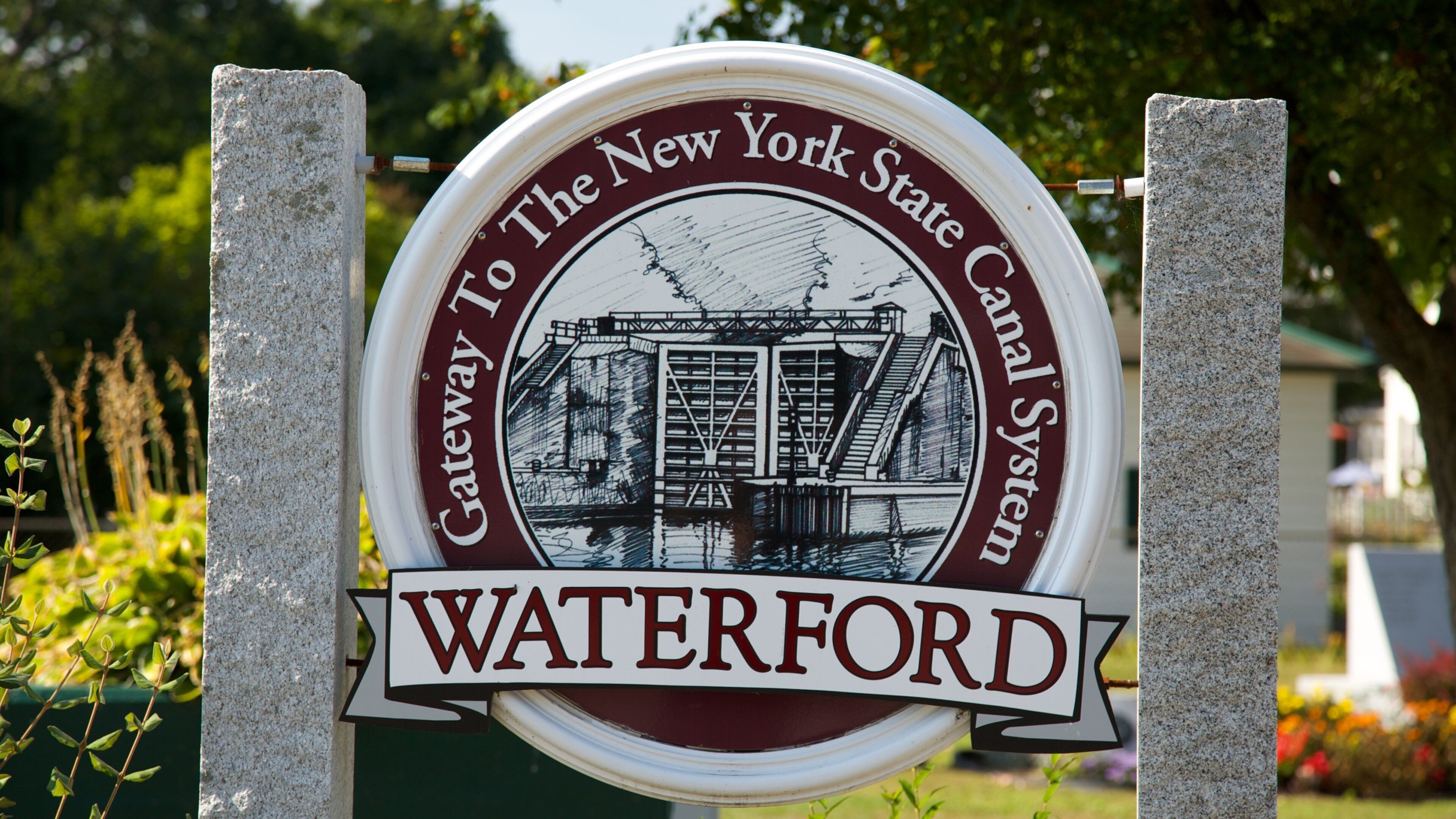 A circular sign with a historical illustration and the text "Gateway to the New York State Canal System" and "Waterford".