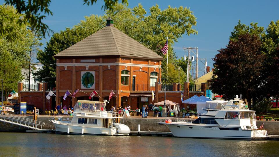 A brick building with a clock tower, a dock with boats, and flags.