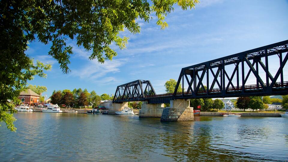 A steel bridge over a river with boats and a building in the background.