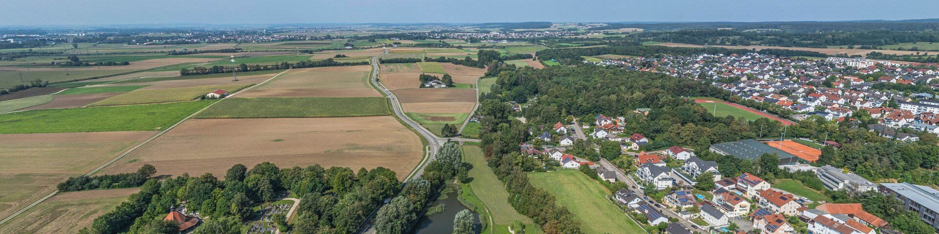 An aerial view of a rural town with fields, a winding road, and residential areas.