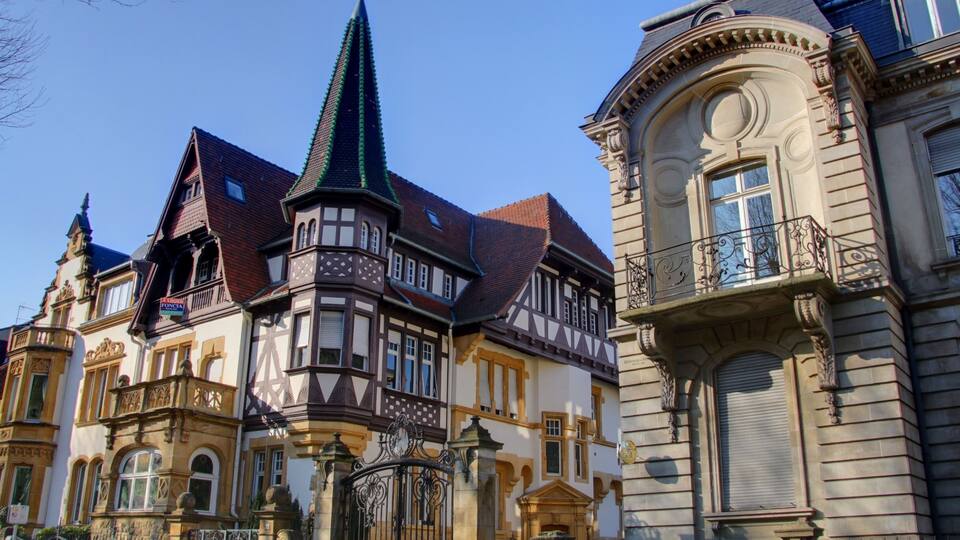 A historic building with a pointed tower and ornate balconies.