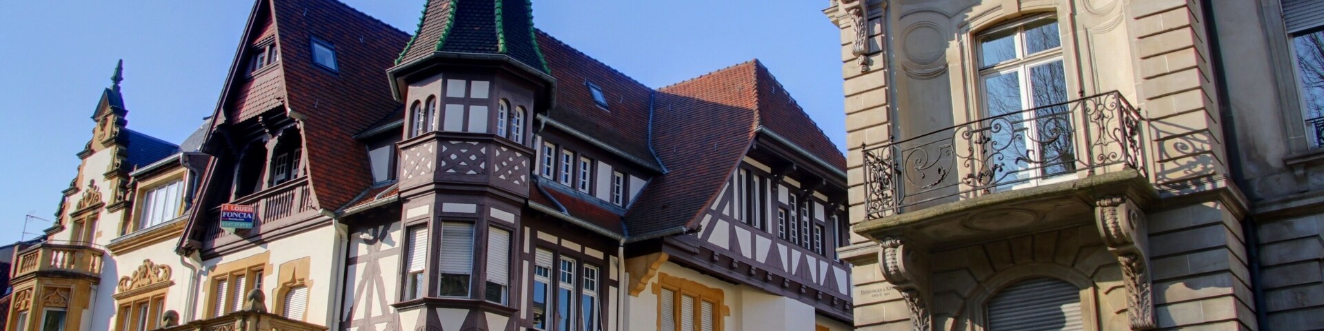 A historic building with a pointed tower and ornate balconies.