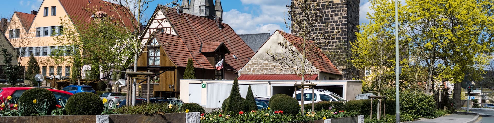 A town square with a church steeple, a clock tower, and residential buildings.