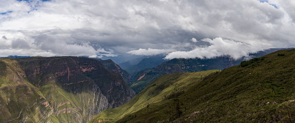 A mountainous landscape with deep valleys and lush green hills.