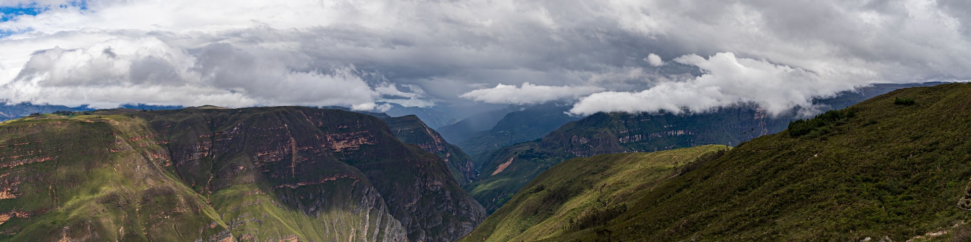 A mountainous landscape with deep valleys and lush green hills.